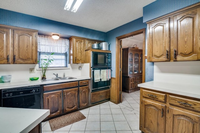 kitchen featuring a sink, light countertops, a textured ceiling, light tile patterned floors, and black appliances