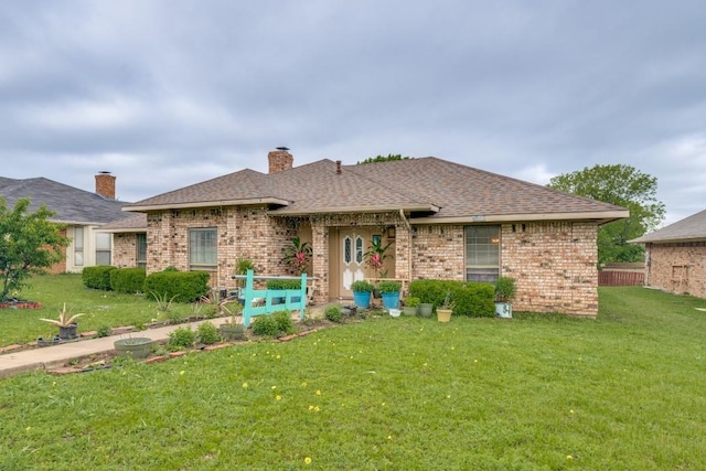 single story home with brick siding, a shingled roof, a front yard, and a chimney