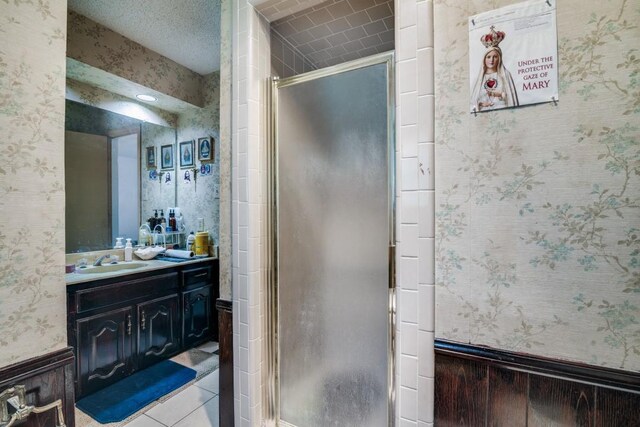 full bath with wallpapered walls, a shower stall, and vanity