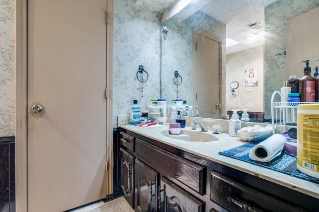 bathroom with vanity, visible vents, and wallpapered walls