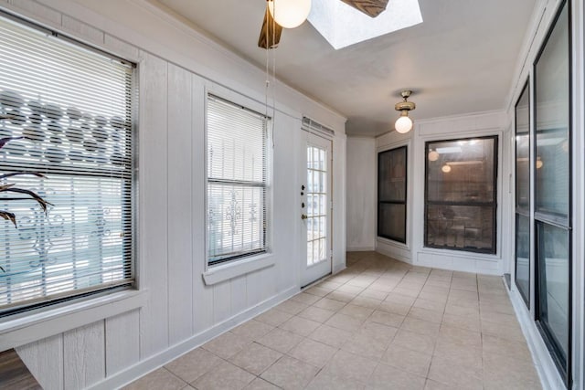 foyer entrance featuring a skylight, light tile patterned floors, ornamental molding, and a ceiling fan