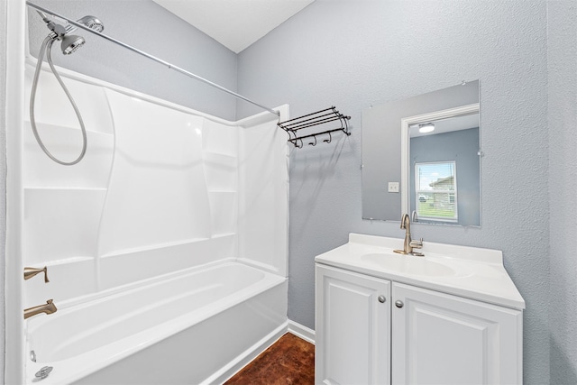 bathroom featuring vanity, baseboards, bathtub / shower combination, and a textured wall