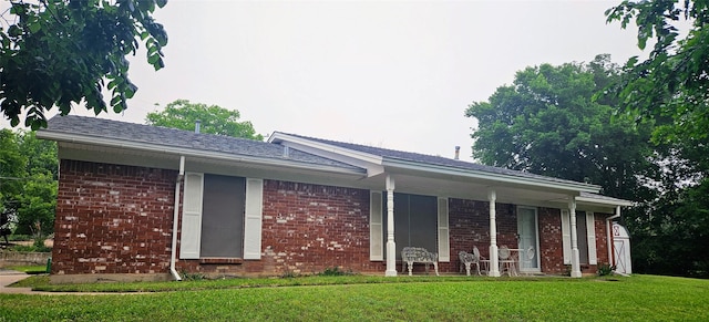 back of house with a yard, a porch, and brick siding