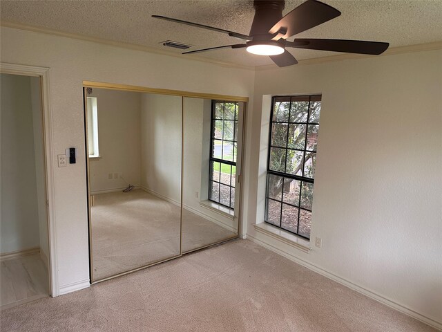 unfurnished bedroom with carpet floors, a textured ceiling, and visible vents