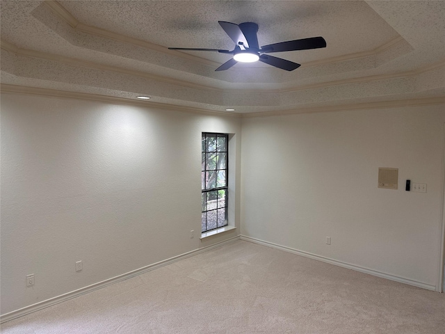 spare room featuring ceiling fan, light carpet, baseboards, and a raised ceiling