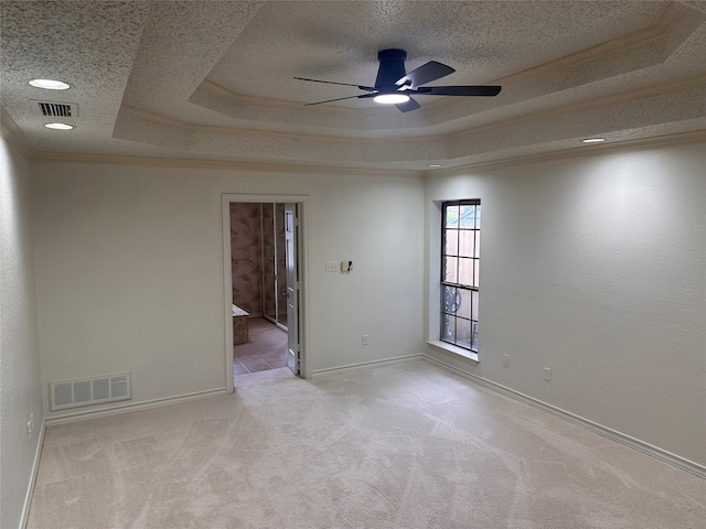 spare room with a raised ceiling, a ceiling fan, carpet floors, and visible vents