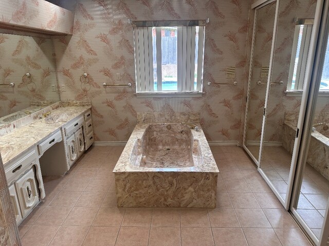 bathroom featuring tile patterned floors, baseboards, a garden tub, and vanity