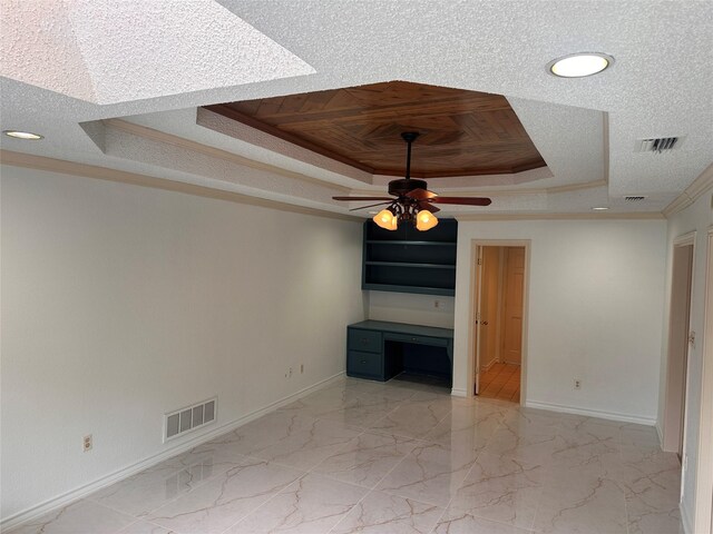 unfurnished living room with crown molding, ceiling fan, a raised ceiling, baseboards, and visible vents