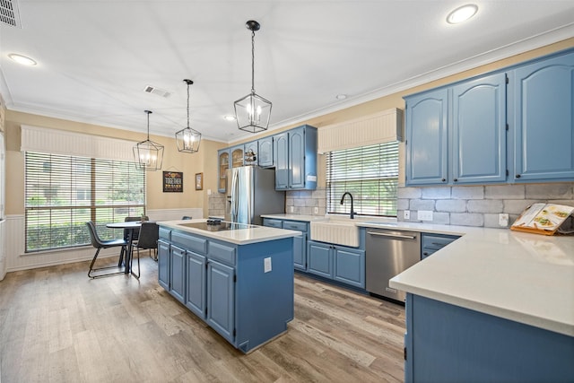 kitchen with ornamental molding, a kitchen island, a sink, appliances with stainless steel finishes, and blue cabinetry
