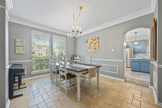 dining space with stone tile floors, an inviting chandelier, and ornamental molding