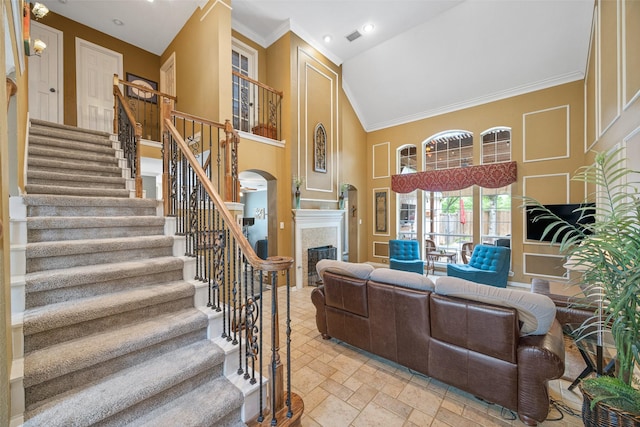 living area with arched walkways, stairway, high vaulted ceiling, a premium fireplace, and stone tile floors