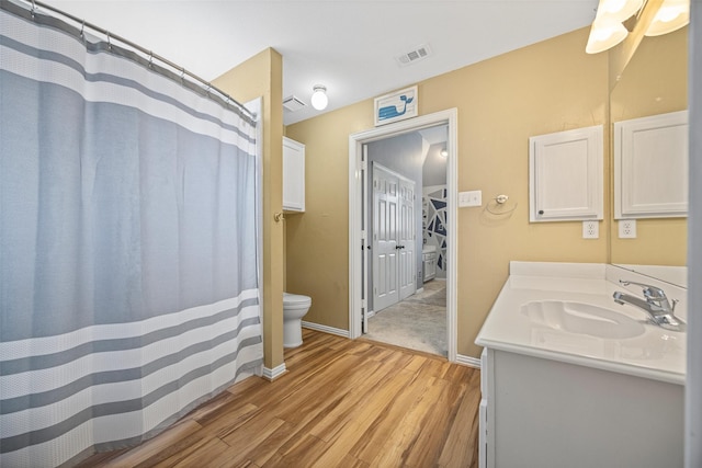 bathroom featuring visible vents, vanity, wood finished floors, toilet, and baseboards