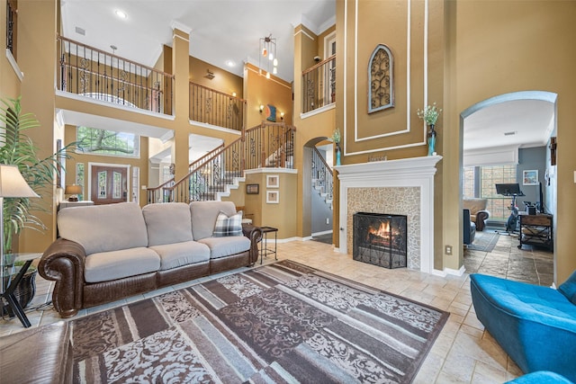 living area with stairs, a high ceiling, baseboards, and stone tile floors