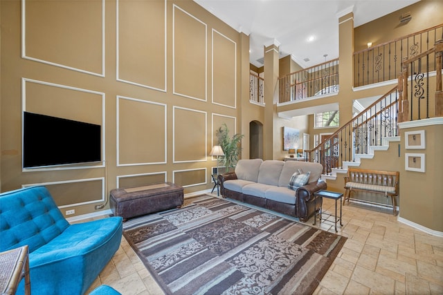 living room featuring stone tile flooring, a towering ceiling, baseboards, stairway, and recessed lighting