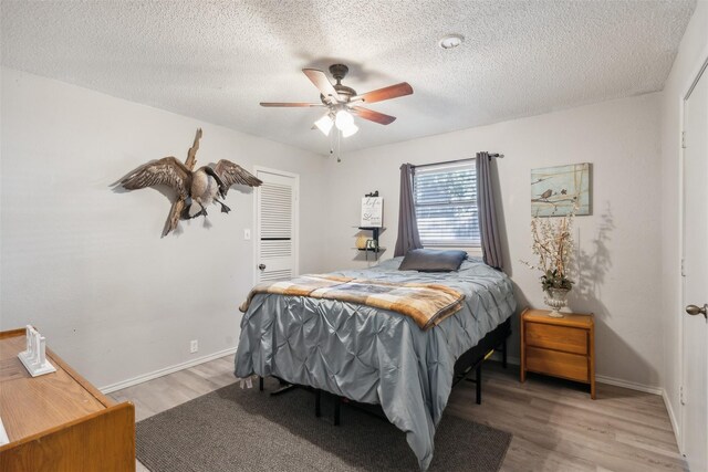 bedroom with light wood-style floors, baseboards, and a textured ceiling