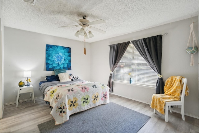 bedroom with a ceiling fan, baseboards, and wood finished floors