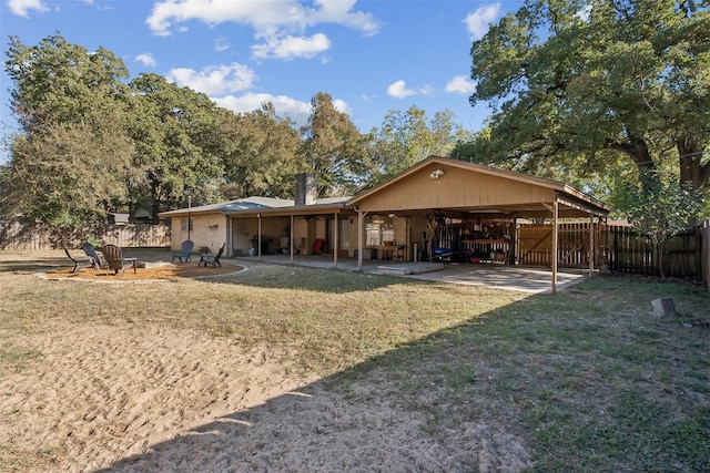 rear view of property with a patio, a lawn, fence, and an outdoor fire pit