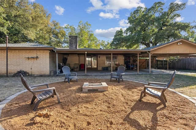 rear view of property with fence, a patio, a chimney, brick siding, and an outdoor fire pit