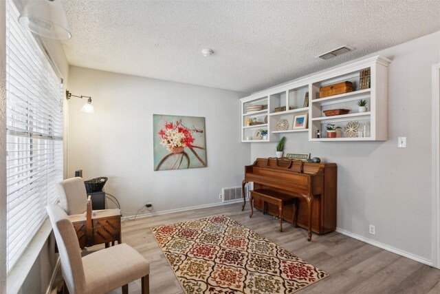 sitting room featuring visible vents, baseboards, a textured ceiling, and wood finished floors