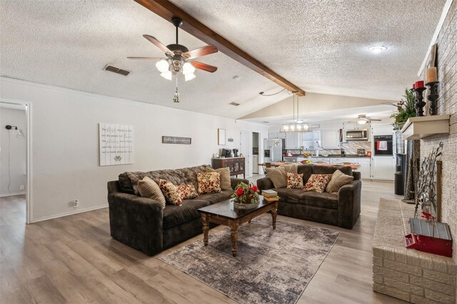 living area featuring visible vents, a ceiling fan, a textured ceiling, and vaulted ceiling with beams