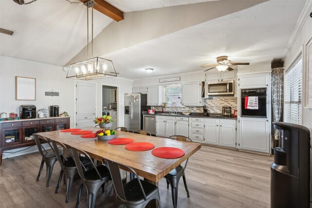 dining room featuring light wood-style floors, plenty of natural light, and vaulted ceiling with beams