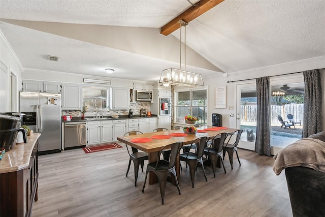 dining room with light wood-style floors, an inviting chandelier, lofted ceiling with beams, and visible vents