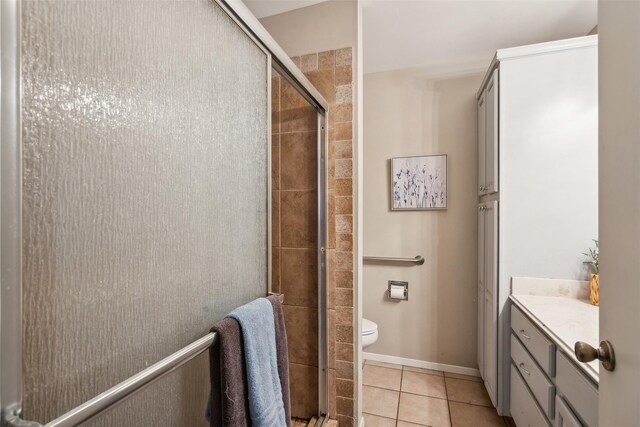 full bath with tile patterned flooring, vanity, toilet, baseboards, and a stall shower