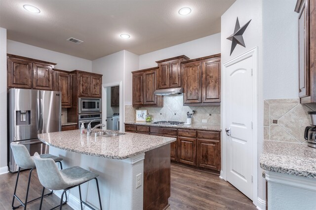 kitchen featuring visible vents, dark wood-style flooring, under cabinet range hood, a sink, and stainless steel appliances