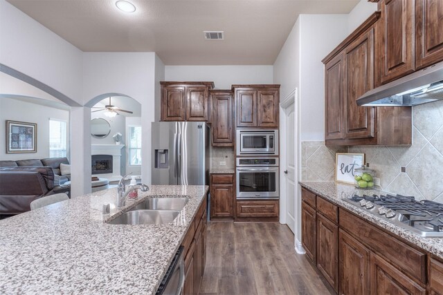 kitchen with ceiling fan, visible vents, appliances with stainless steel finishes, light stone countertops, and a sink