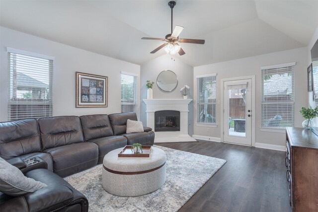 living room featuring dark wood-style flooring, a glass covered fireplace, a ceiling fan, baseboards, and lofted ceiling