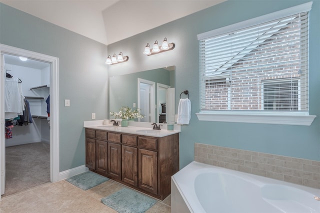 full bath with a sink, tile patterned flooring, double vanity, a spacious closet, and a garden tub