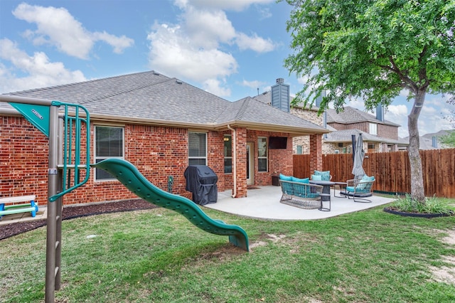 rear view of property with fence, roof with shingles, brick siding, a playground, and a yard