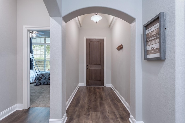 hall with arched walkways, baseboards, and dark wood-style floors