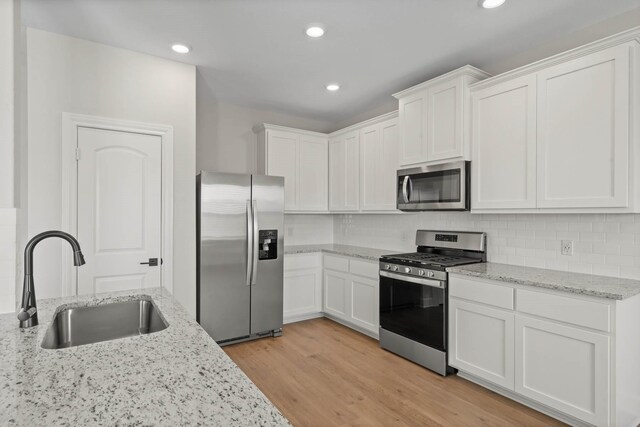 1105 Dye Blvd, Princeton, TX 75407 - kitchen featuring appliances with stainless steel finishes, a sink, white cabinets, light wood-style floors, and recessed lighting