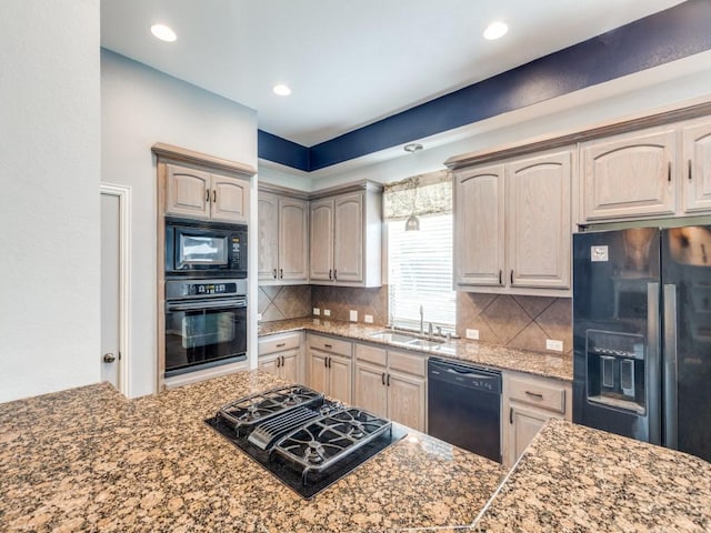 kitchen featuring recessed lighting, a sink, dark stone countertops, backsplash, and black appliances