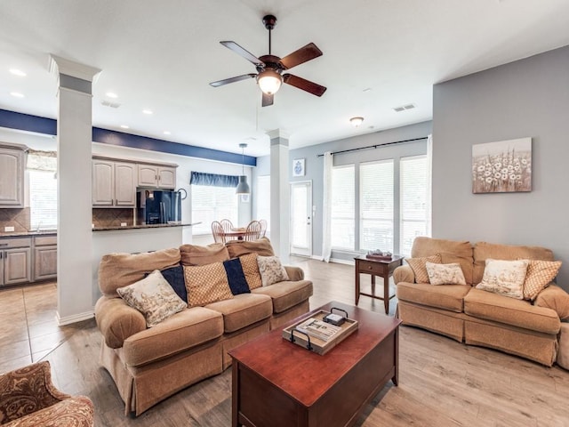 living room with ceiling fan, ornate columns, and a wealth of natural light