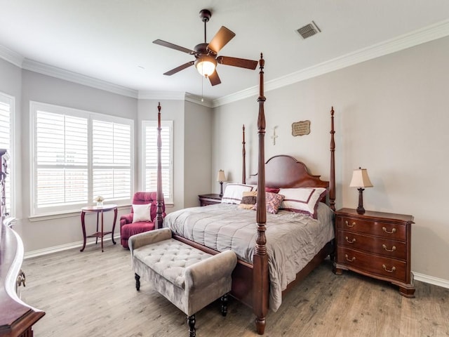 bedroom with visible vents, baseboards, wood finished floors, and multiple windows