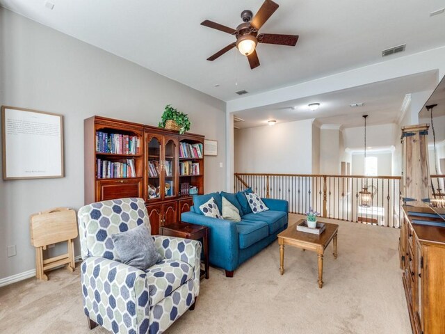 living area with light colored carpet, ceiling fan, visible vents, and an upstairs landing