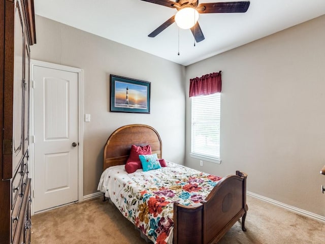 bedroom featuring light colored carpet, a ceiling fan, and baseboards