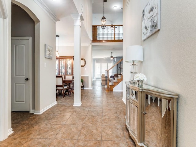 foyer featuring a ceiling fan, baseboards, stairway, arched walkways, and light tile patterned floors