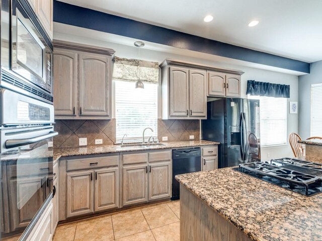 kitchen featuring decorative backsplash, light stone countertops, a sink, light tile patterned floors, and black appliances