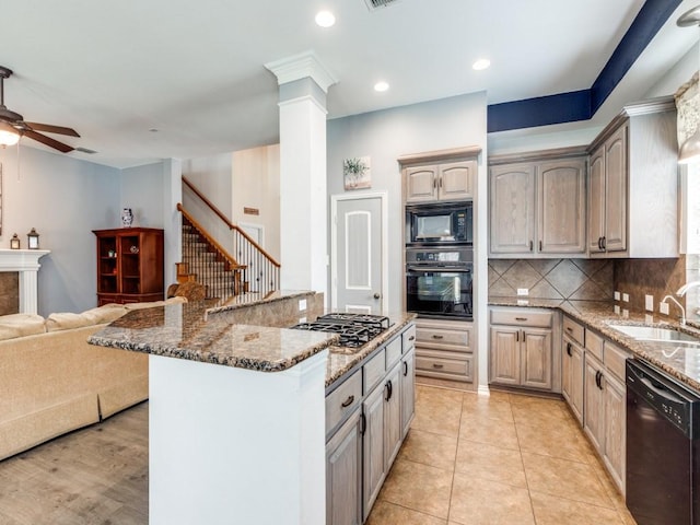 kitchen with a sink, stone counters, black appliances, and open floor plan