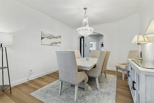 dining space with arched walkways, ornamental molding, wood finished floors, and baseboards