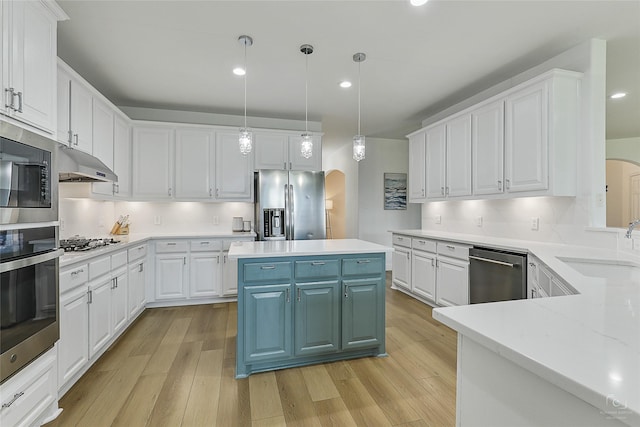 kitchen featuring arched walkways, stainless steel appliances, white cabinetry, a sink, and recessed lighting