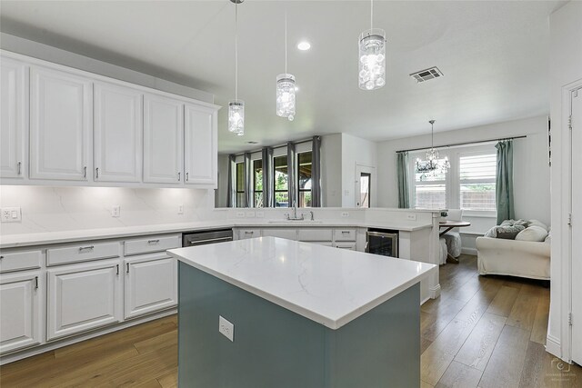 kitchen featuring a sink, hardwood / wood-style floors, a chandelier, a kitchen island, and white cabinetry