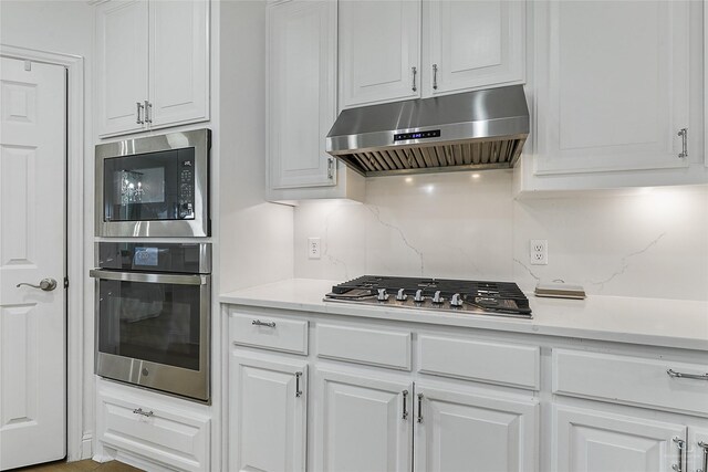 kitchen featuring appliances with stainless steel finishes, under cabinet range hood, light countertops, and white cabinets