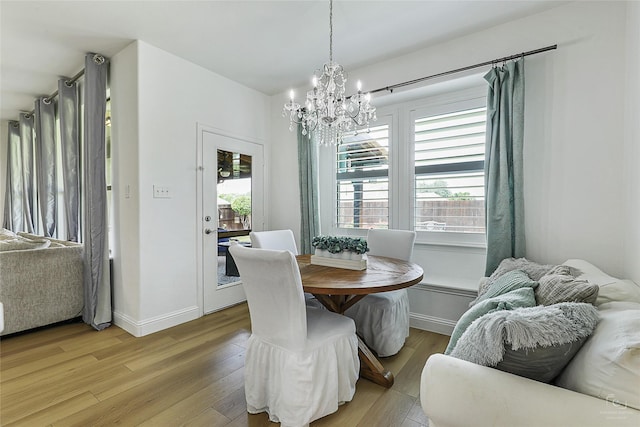 dining space with a chandelier, light wood finished floors, and baseboards