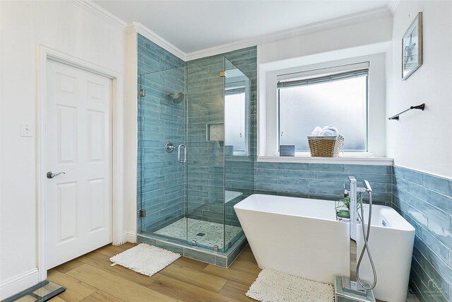 full bathroom with tile walls, a shower stall, crown molding, wood finished floors, and a soaking tub