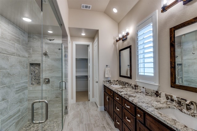 bathroom featuring visible vents, a sink, double vanity, and a shower stall