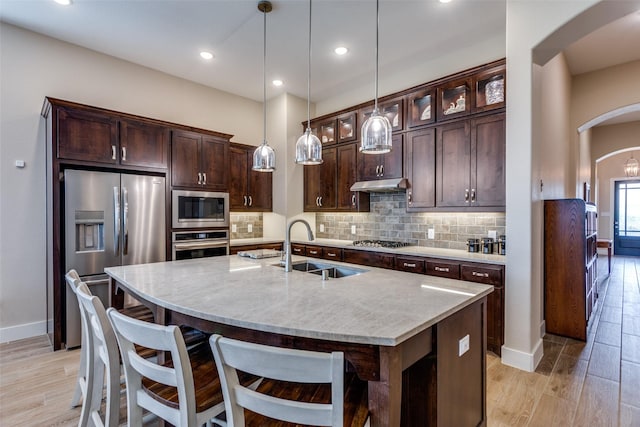 kitchen with baseboards, stainless steel appliances, arched walkways, and a sink
